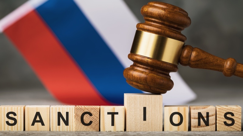 judge's gavel, wooden cubes with the text on the background of the Russian flag, the concept on the topic of sanctions in Russia